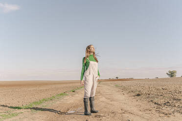 Junge Frau auf trockenem Feld stehend, mit geschlossenen Augen - ERRF02295