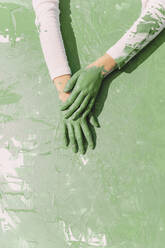 Green hands of young woman on green painting - ERRF02367