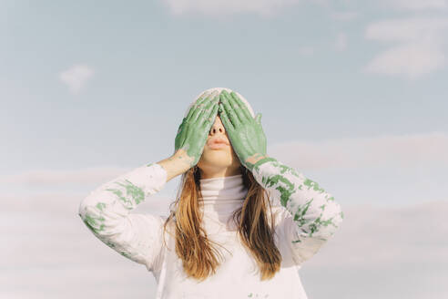 Young woman covering eyes with green hands - ERRF02396