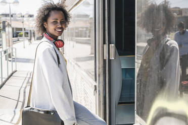 Portrait of a smiling young woman entering a train - UUF19758