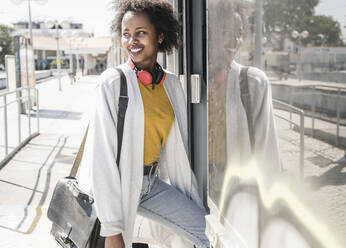 Smiling young woman entering a train - UUF19759