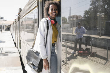 Happy young woman entering a train - UUF19760