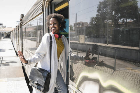 Lächelnde junge Frau beim Einsteigen in einen Zug, lizenzfreies Stockfoto