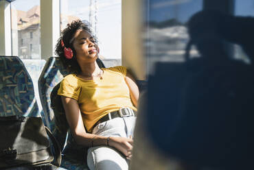 Young woman with headphones relaxing in a train - UUF19786