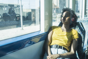 Young woman with headphones relaxing in a train - UUF19787