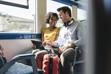 Happy young couple using tablet in a train - UUF19792