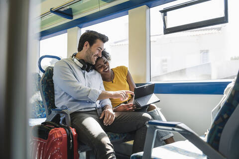 Glückliches junges Paar benutzt Tablet in einem Zug, lizenzfreies Stockfoto