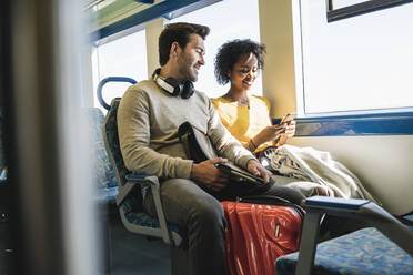 Young couple with smartphone relaxing in a train - UUF19794