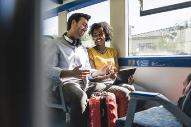 Happy young couple using tablet in a train - UUF19795