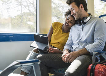 Young couple with tablet relaxing in a train - UUF19796