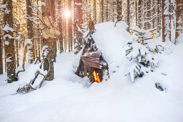 Österreich, Salzburg, Altenmarkt-Zauchensee, Kleine Holzhütte und Lagerfeuer in tief verschneitem Wald - HHF05594