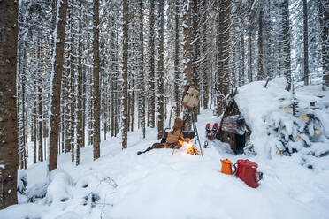 Austria, Salzburg, Altenmarkt-Zauchensee, Small wooden hut and campfire in forest covered with deep snow - HHF05596