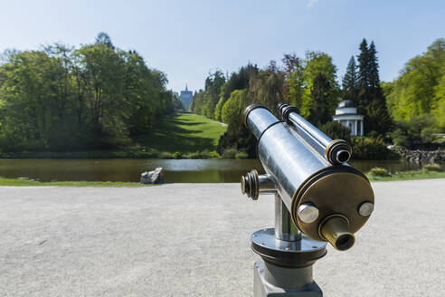 Deutschland, Hessen, Kassel, Münzbetriebenes Fernglas vor einem Teich im Bergpark Wilhelmshöhe - RUNF03501