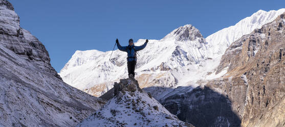 Ein Bergsteiger jubelt auf einem Felsen, Dhaulagiri Circuit Trek, Himalaya, Nepal - ALRF01642