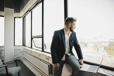 Geschäftsmann mit Laptop im Coworking Space - KNSF06994