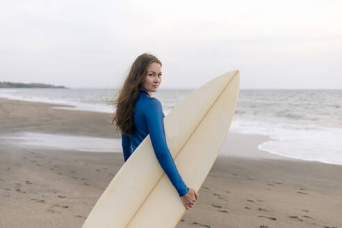 Young woman with surfboard at the beach, Kedungu beach, Bali, Indonesia - KNTF03810