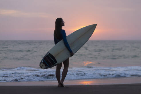 Junge Frau mit Surfbrett am Strand, Kedungu Strand, Bali, Indonesien - KNTF03818