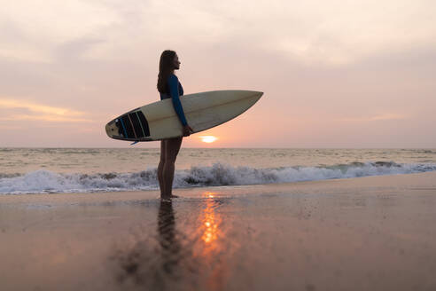 Young woman with surfboard at the beach, Kedungu beach, Bali, Indonesia - KNTF03819