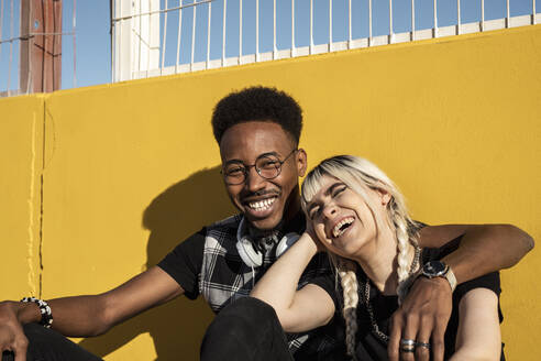 Portrait of laughing young couple against yellow wall - RCPF00157