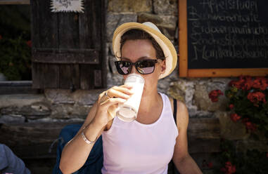 Frau genießt ein Glas Buttermilch auf einer Berghütte, Passeiertal, Südtirol, Italien - DIKF00317
