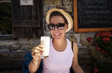 Woman enjoying a glass of buttermilk at a mountain hut, Passeier Valley, South Tyrol, Italy - DIKF00318