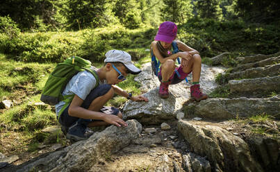 Junge und Mädchen beim Wandern, Ameisen beobachten, Passeiertal, Südtirol, Italien - DIKF00319