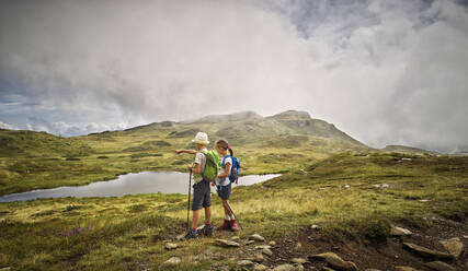 Boy and girl standing at a lake in alpine scenery, Passeier Valley, South Tyrol, Italy - DIKF00331