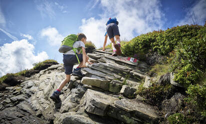Junge und Mädchen klettern in den Bergen auf einen Felsen, Passeiertal, Südtirol, Italien - DIKF00335