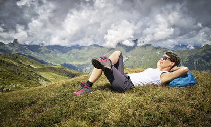 Frau, die auf einer Almwiese liegend eine Wanderpause einlegt, Passeiertal, Südtirol, Italien - DIKF00338
