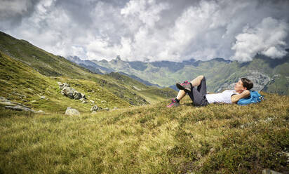 Woman having a break from hiking lying on alpine meadow, Passeier Valley, South Tyrol, Italy - DIKF00339