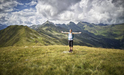 Fröhliche Frau, die auf einer Almwiese stehend eine Wanderpause einlegt, Passeiertal, Südtirol, Italien - DIKF00345