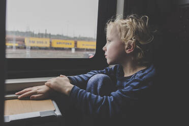 Little boy sitting in train looking out of window - IHF00221