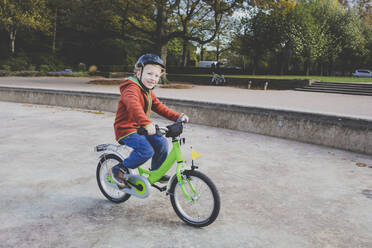 Porträt eines lächelnden kleinen Jungen auf dem Fahrrad - IHF00223