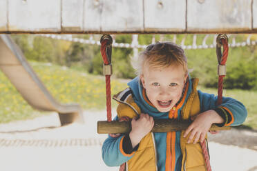 Porträt eines blonden kleinen Jungen auf einem Spielplatz - IHF00237