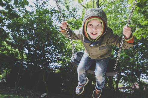 Porträt eines glücklichen kleinen Jungen auf einer Schaukel - IHF00252