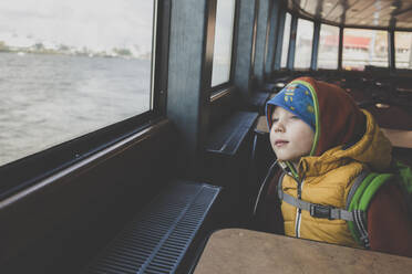 Porträt eines kleinen Jungen, der aus dem Fenster einer Fähre schaut - IHF00254