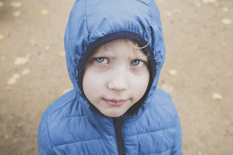 Porträt eines mürrischen kleinen Jungen mit blauem Anorak, lizenzfreies Stockfoto