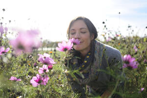 Porträt einer Frau, die an einer Wildblume riecht, Blumenwiese - ECPF00789