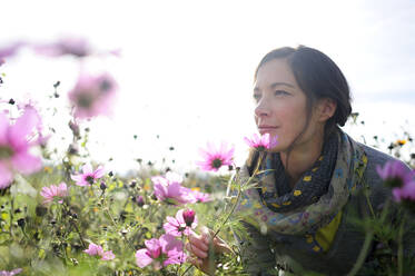 Porträt einer Frau, die an einer Wildblume riecht, Blumenwiese - ECPF00790