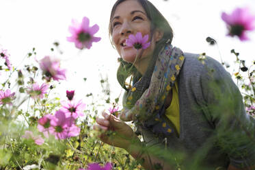 Porträt einer Frau, die an einer Wildblume riecht, Blumenwiese - ECPF00791