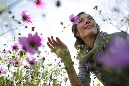 Porträt einer Frau, die an einer Wildblume riecht, Blumenwiese - ECPF00792