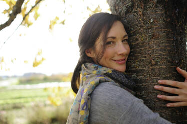 Porträt einer Frau, die einen Baum umarmt - ECPF00798