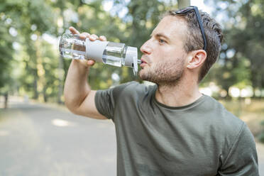 Man drinking water after workout outdoors - FBAF01097