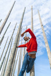 Young man moving and dancing between wood poles - AFVF04637