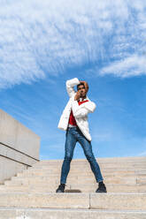 Young man standing on stairs outdoors with hands on face - AFVF04638