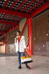 Young man with smartphone and bag outdoors - AFVF04660