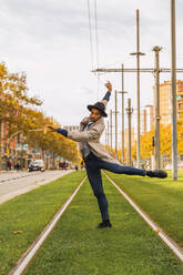 Junger Mann bewegt sich und tanzt auf Straßenbahnschienen - AFVF04672