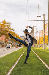 Junger Mann bewegt sich und tanzt auf Straßenbahnschienen - AFVF04673