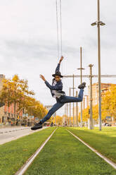 Junger Mann springt und tanzt auf Straßenbahnschienen - AFVF04675