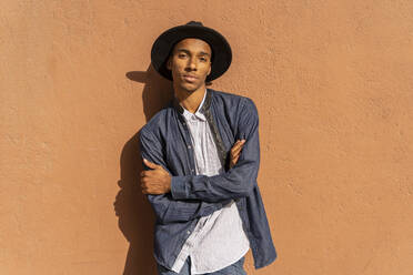 Porträt eines stilvollen jungen Mannes mit Hut an einer Wand - AFVF04685